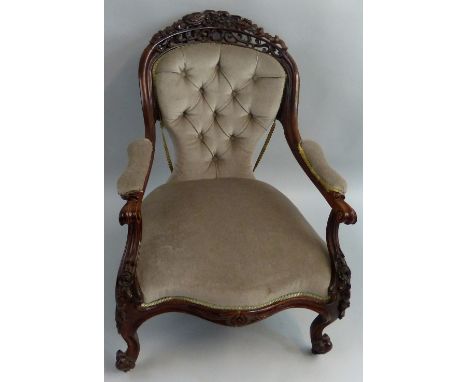A Victorian rosewood framed armchair, the deep buttoned balloon shaped back and floral and scroll carved and pierced crest ra