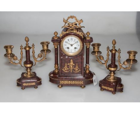 A late 19th century French rouge marble and ormolu mounted clock garniture, in the manner of Samuel Marti, the clock with arc