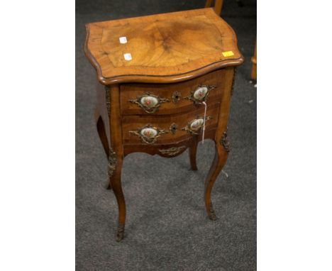 A French early 20th century serpentine fronted petit commode, with caroutche shaped top, fitted with Limoges panels and gilt 