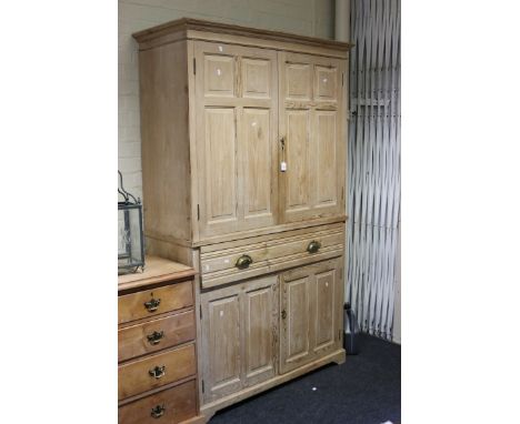 A 20th century pine press cupboard, the moulded cornice over a pair of fielded panel doors enclosing shelves, the base having