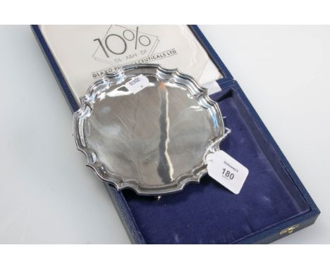 A silver salver, circular with pie-crust border, on four leaf capped scroll feet, Sheffield 1986, 6oz, in fitted commemorativ