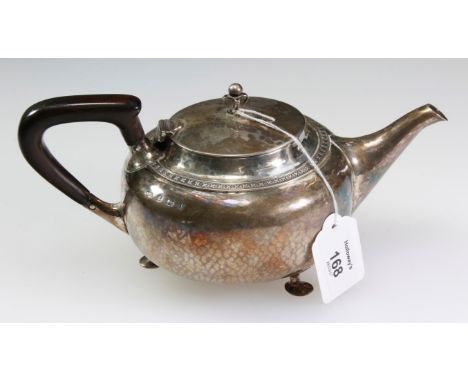 An early 20th century Arts and Crafts silver teapot, of squat hammered form, with open work and bead finial and shaped ebony 