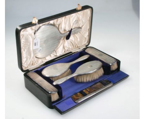 A cased five piece silver dressing table set, comprising a hand mirror, a pair of hair brushes and a pair of clothes brushes,