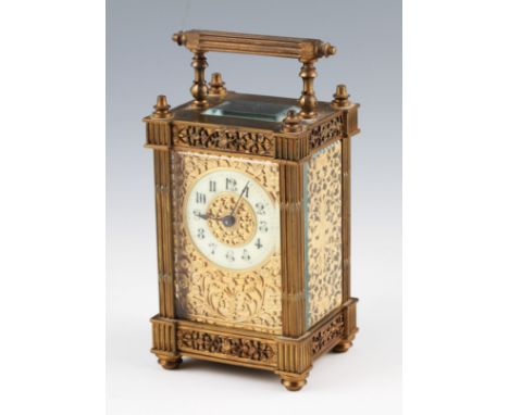 A 20th Century French carriage clock having ornate openwork gilt scroll and foliage design to sides and front, having cream c