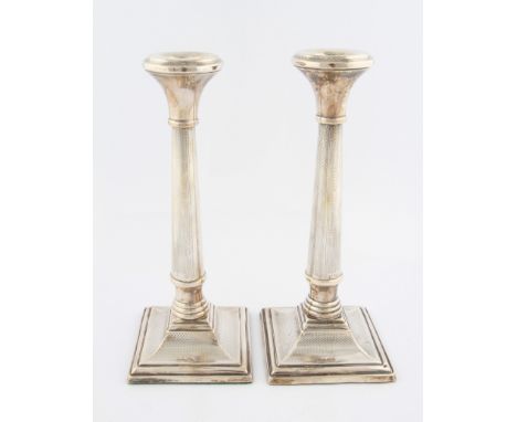 A pair of weighted silver candlesticks, of columnar form with engine turned design, on a square base, hallmarked Birmingham 1