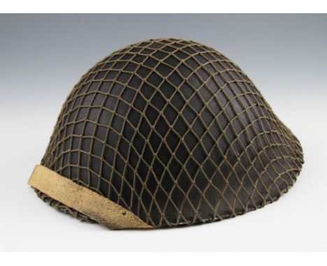 A 1944 pattern helmet in dark green with netting and liner, dated 1945.