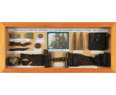 A small framed and glazed display case containing WW1 relics from Ypres containing snake clasp buckle, ammunition, coins etc.