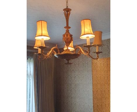 An Italian gilt metal five branch chandelier, central urn support section applied with scrolling motifs, with scrolling folia