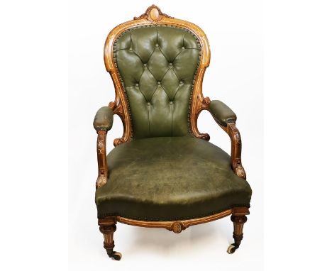 A Victorian inlaid mahogany framed large library armchair, the shaped leather button upholstered back surmounted by carved ov