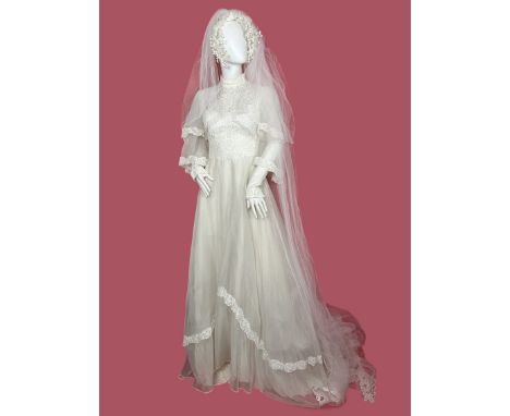 A 1970s wedding dress with high neck and tiered anged sleeves made from a nylon voile with guipure lace trim and bodice. The 