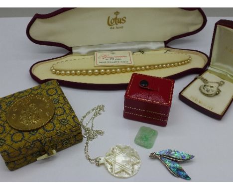 A collection of jewellery including a silver and abalone brooch, a silver locket, Chinese jade charm, a Lotus simulated pearl