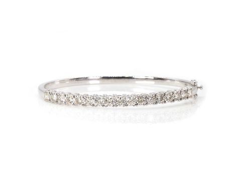 A 9ct white gold diamond hinged bangle, with round brilliant cut diamonds illusion set to the top, into a plain D section low