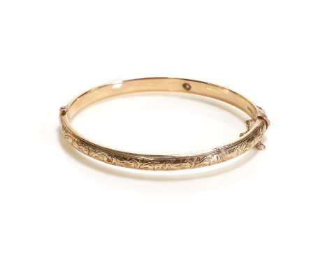 An Edwardian 9ct gold bangle, the hollow hinged bangle half decorated with swirl engravings, with tongue and clip clasp and s