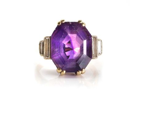 An amethyst and diamond cocktail ring,  featuring a large octagonal step cut amethyst, claw set, with two baguette cut diamon