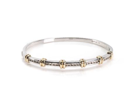 A 9ct two colour gold diamond hinged bangle, featuring a line of channel set round brilliant cut diamonds, with a total weigh