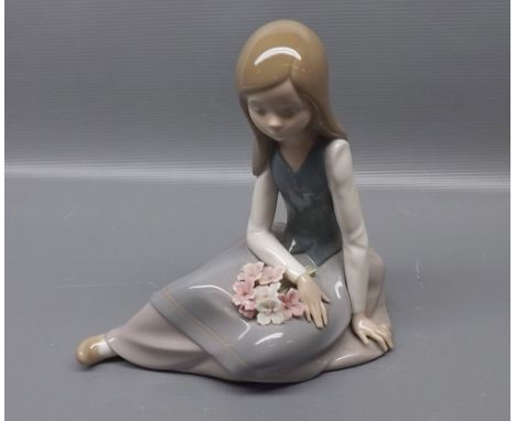Lladro figure of a seated young girl with flowers on her dress, 7 ins tall  