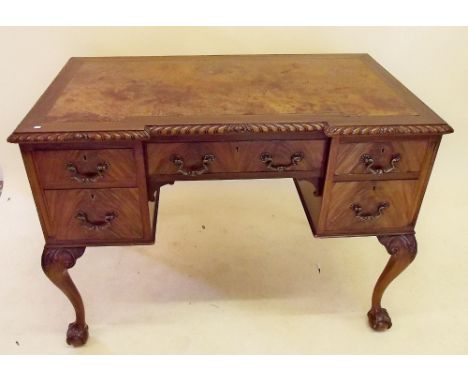 An early 20th century Chippendale style mahogany desk with leather inset top over five drawers all raised on claw and ball su