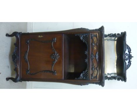 A late Victorian carved mahogany music cabinet, the bevelled mirror panelled superstructure with a shallow shelf on supports,