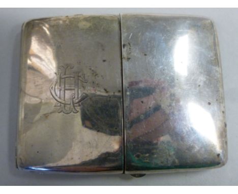 An Edwardian silver curved, cushion shaped cigarette case, the pair of hinged flaps, on opposing button clasps, enclosing thr
