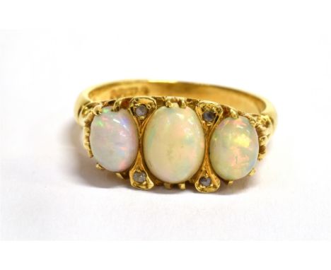A THREE STONE OPAL 18CT GOLD RING  the three oval cabochon cut opals with small diamond points between, the centre opal appro