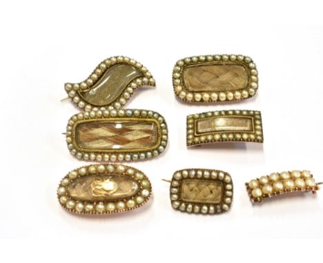 SEVEN 19TH CENTURY SEED PEARL SET MOURNING BROOCHES Of assorted shapes, six of them with plaited hair to glazed centre and se