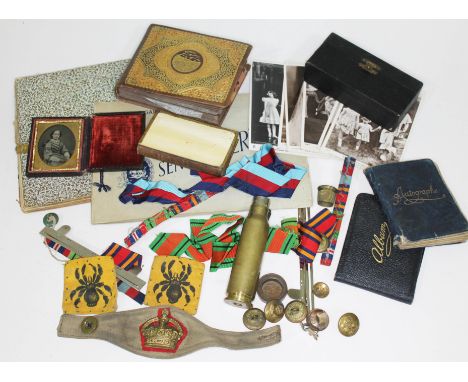 A mixed lot to include a cigarette card album, military ribbons and badges, a trench art table lighter, postcards, photograph