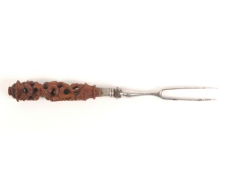 A late 18th Century/early 19th Century French twin prong fork with pierced and carved boxwood handle, with a figure by a wall