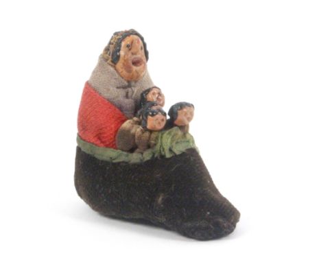 A novelty pin cushion 'There was an old woman who lived in her shoe', the old woman in shawl and cloak with four children in 