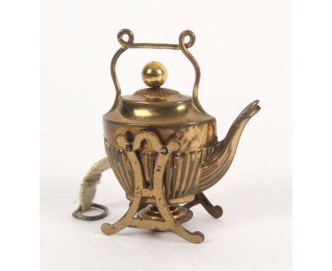 A gilt brass novelty tape measure in the form of a tea kettle on stand, the complete printed tape in ins. and cm. and wound f