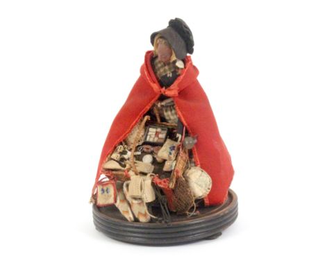 A good example of a Victorian pedlar doll, on ebonised base under a glass dome, the doll with painted face, black bonnet and 