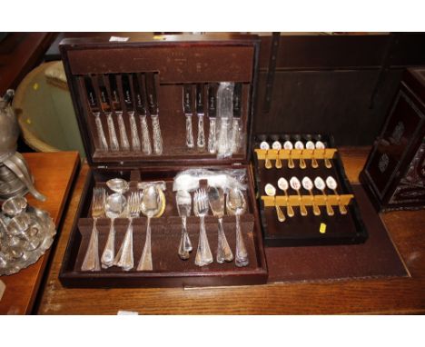 A canteen of plated cutlery and a set of 12 enamel decorated teaspoons mounted to a rack