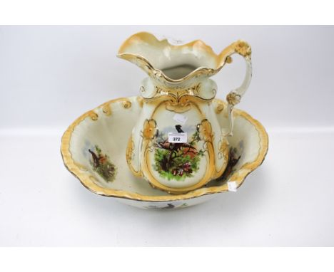 A ceramic pitcher and basin. Both decorated with a scene of pheasants and gilt details, H36cm