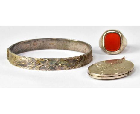 Three pieces of hallmarked silver jewellery, comprising a hinged bangle with floral engraving, a large oval locket with flora