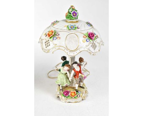 A Continental porcelain figural table lamp, the shade pierced and encrusted with flowers, on a base with dancing children, on