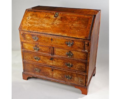 George I walnut bureau, the rectangular top above a cross banded sloping fall enclosing a series of drawers above a long draw