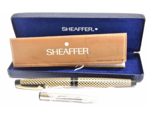 A SCHEAFFER FOUNTAIN PEN the black case with gold coloured wave design pattern, white dot to top of clip, medium in gold lett