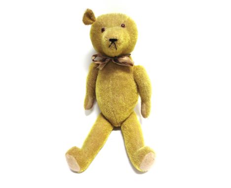 A GOLD MOHAIR TEDDY BEAR  circa 1930s, probably English, with orange glass eyes and a black horizontally stitched nose, on a 