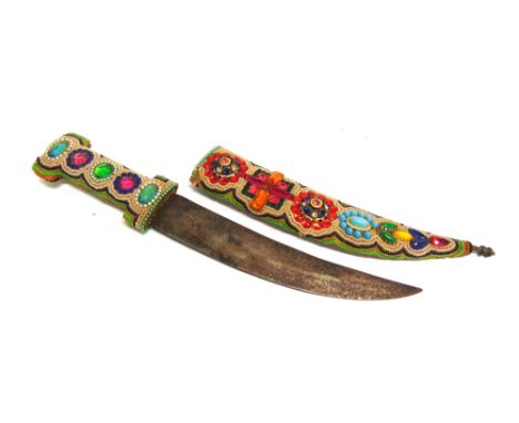 A JAMBIYA STYLE DAGGER  the 24.5cm blade with a crowned head motif to one side, the grip and scabbard with beaded and faux ge