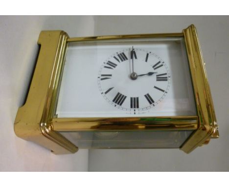 A mid 20thC lacquered brass cased carriage clock, having bevelled glass panels and a folding top handle, on a bracket plinth;