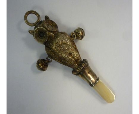 An Edwardian child's silver rattle, featuring a double sided, standing owl, a fixed ring attachment with two pendant bells an