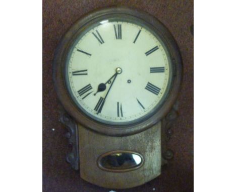 A late 19thC oak cased, drop dial wall clock with an oval, glazed, pendulum window, scroll carved flanks and a hinged access 
