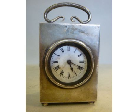 A silver box cased traveller's timepiece with a folding top handle and a circular window, on bun feet; the French movement fa