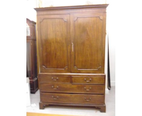 A George III mahogany linen press, having a dentil moulded cornice, over a pair of panelled doors, enclosing four slides, abo