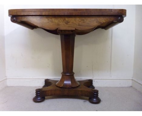 An early Victorian mahogany card table, having a rotating fold-over top, enclosing a baise lined interior, over a shaped frie