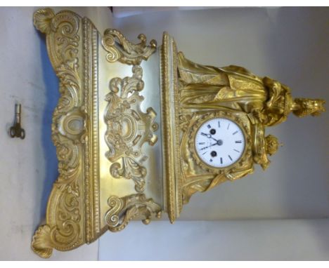 A late 19thC French cast gilt metal cased mantel clock, featuring a standing, regal female figure beside a crown on a cushion