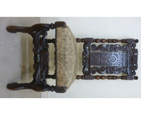A 17thC oak framed side chair, the high back with profusely carved floral and foliate scrolled ornament, having a central pla