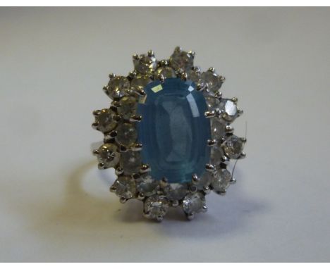 An 18ct white gold cluster ring, set with a central light blue stone (possibly aquamarine) within a twenty-four stone diamond