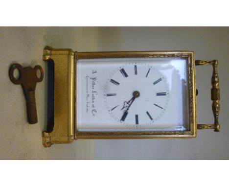 An early 20thC decoratively engraved lacquered gilt metal cased carriage clock, having bevelled glass panels and a folding to