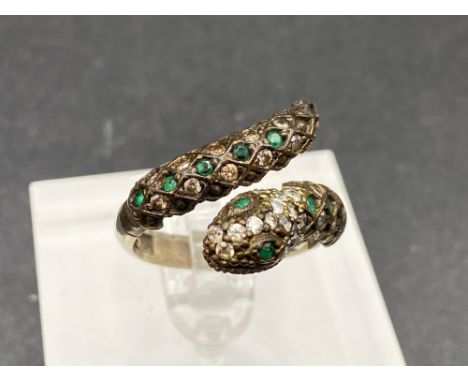 A vintage snake ring with green and white gem stones in white metal size R
