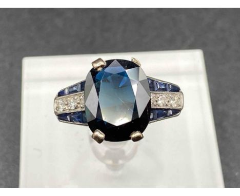 A ART DECO SAPPHIRE AND DIAMOND RING THE LARGE SAPPHIRE IN DIAMOND AND CALIBRATED DIAMOND SHOULDERS SIZE M 6.2 GMS